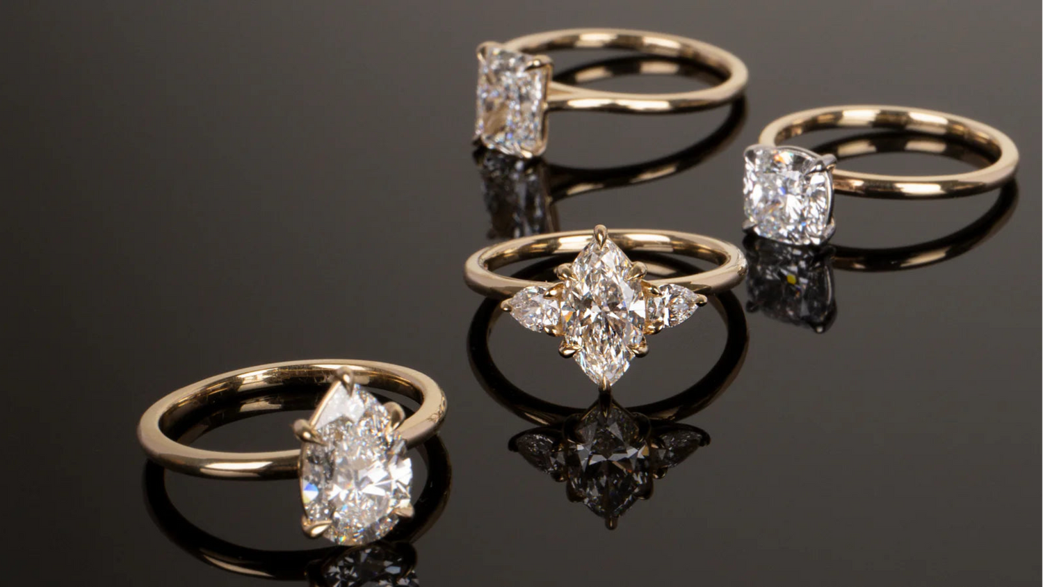 Four elegant lab grown diamond engagement rings with unique cuts displayed on a reflective black surface by Chatoyer Diamonds Perth