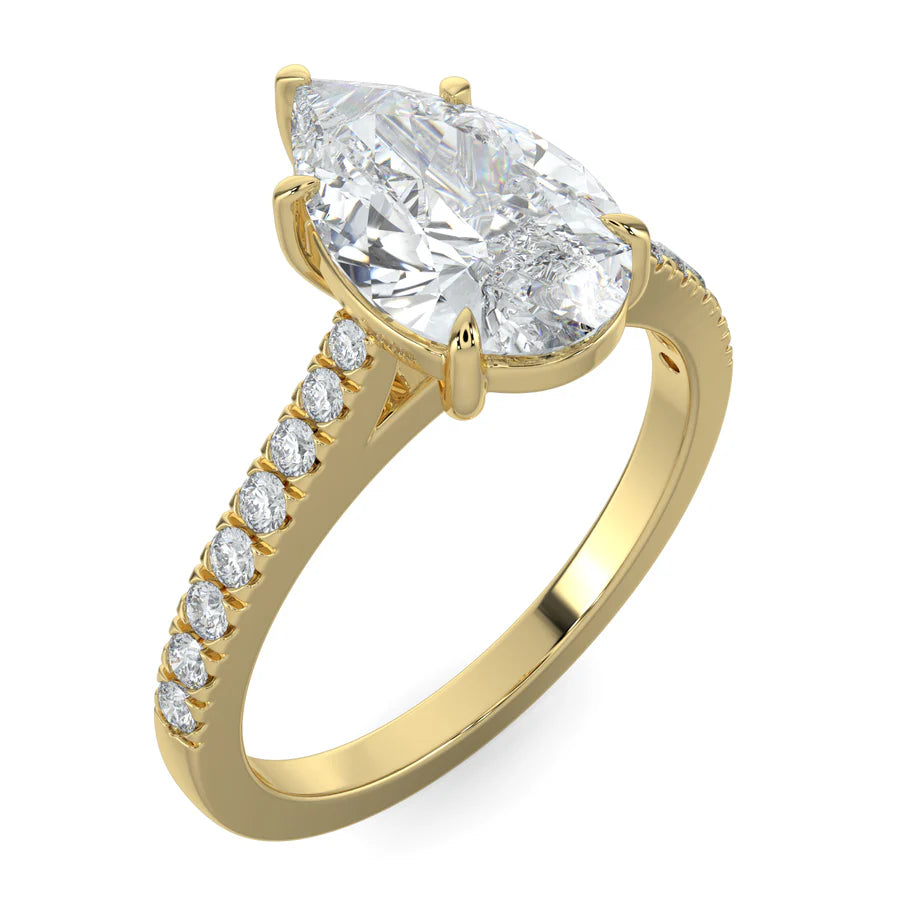 Angled view of a gold lab diamond ring featuring small diamonds on the band and a larger pear shaped central diamond in five prong setting.