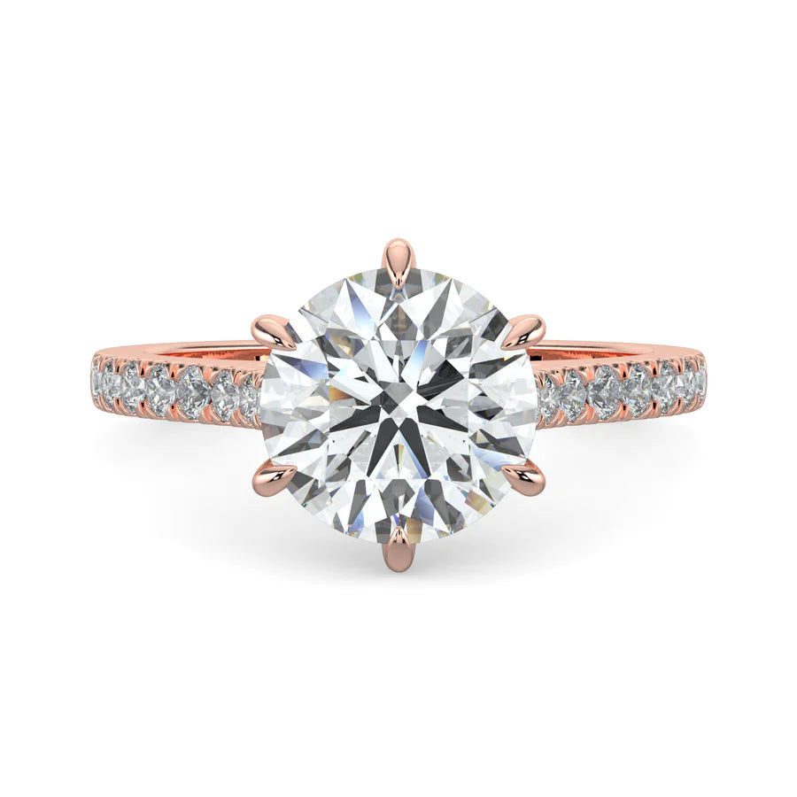 A round lab diamond ring in rose gold color featuring small diamonds on the band and a larger central diamond in six prong setting.