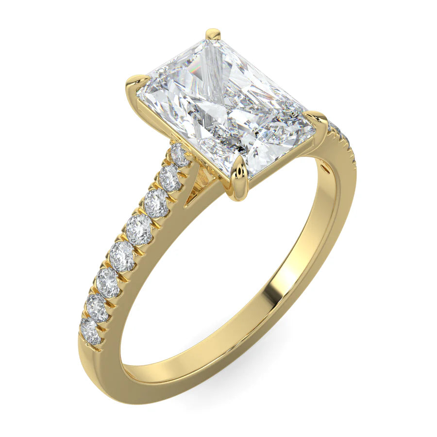 Angled view of a gold lab diamond ring featuring small diamonds on the band and a larger square shaped central diamond in  in four prong setting.